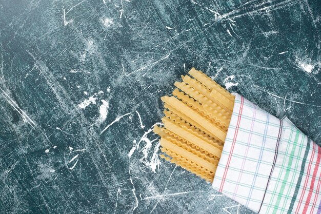 Pâtes crues jaunes avec nappe sur fond bleu. Photo de haute qualité