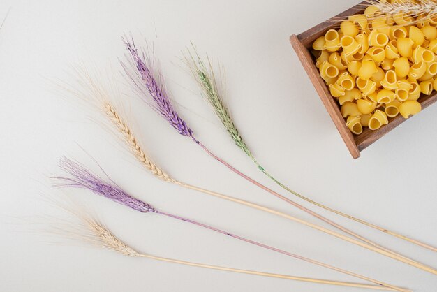 Pâtes crues sur plaque en bois avec des épis de blé colorés