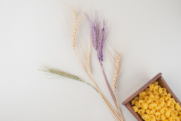 Pâtes crues sur plaque en bois avec des épis de blé colorés