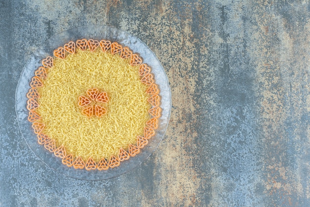 Pâtes dans un bol en verre, sur la surface en marbre.