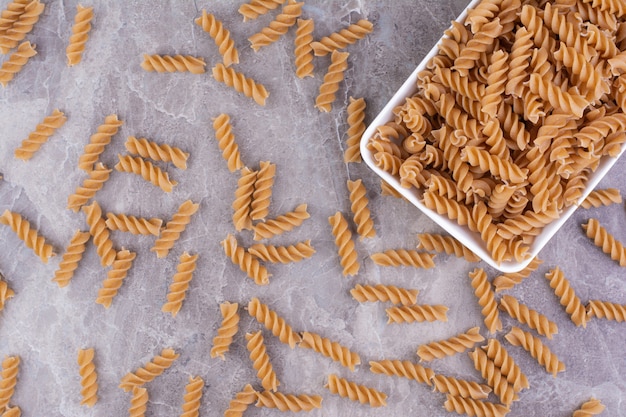 Pâtes dans un plateau en céramique blanche sur le marbre