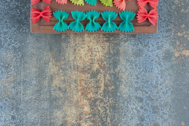 Pâtes farfalle colorées sur le plateau, sur le fond de marbre.