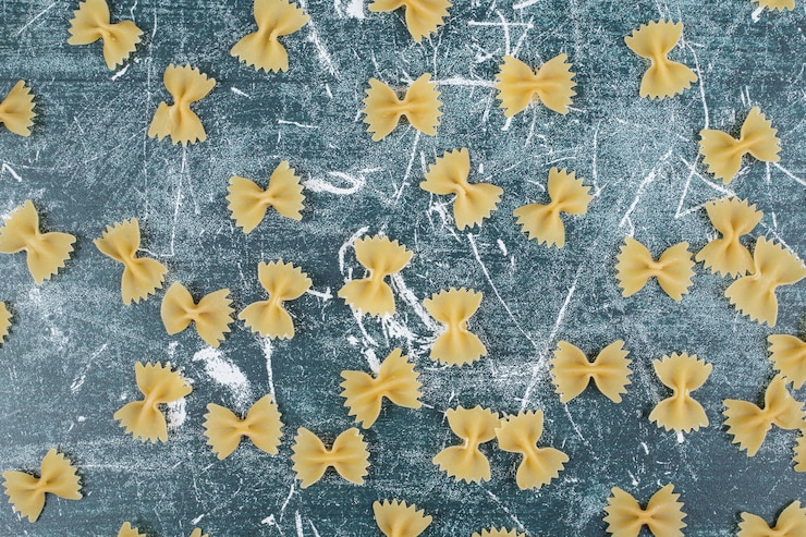 Photo gratuit pâtes farfalle crues éparpillées sur fond bleu. photo de haute qualité