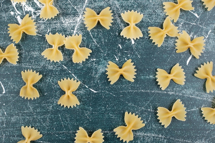 Photo gratuit pâtes farfalle crues éparpillées sur fond bleu. photo de haute qualité