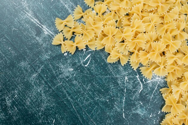 Pâtes farfalle crues sur l'espace bleu.