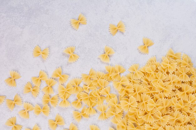 Pâtes farfalle crues sur surface blanche