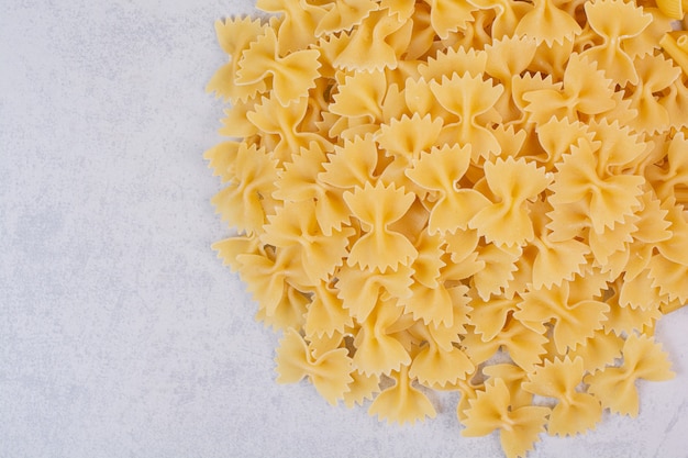 Pâtes farfalle crues sur surface blanche