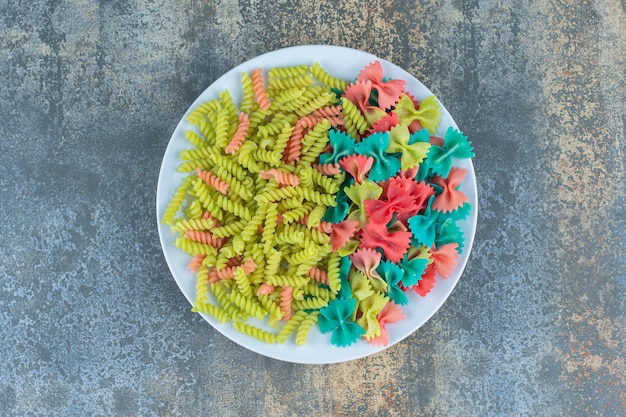 Pâtes Farfalle et fusilli sur l'assiette, sur la surface en marbre.