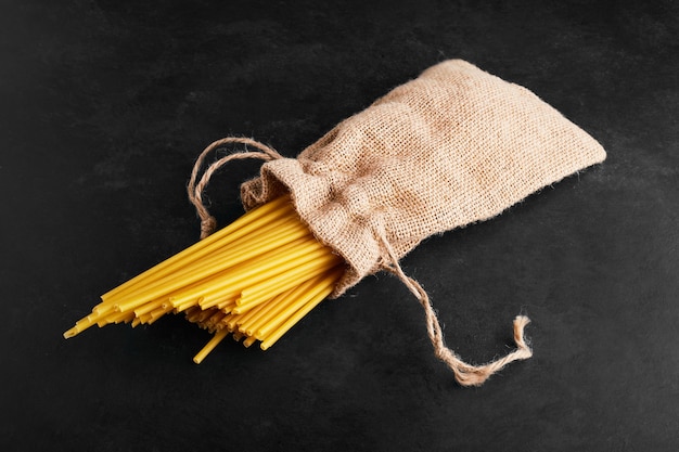 Pâtes sur fond noir dans un colis de toile de jute.