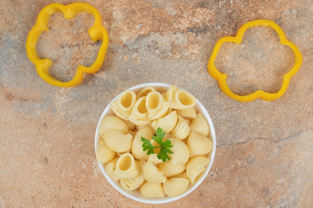 Photo gratuite pâtes en forme de coquillage et tranches de poivron sur fond orange