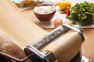 Photo gratuite les pâtes fraîches et la machine sur la table de la cuisine