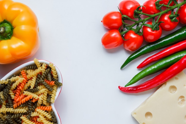 Pâtes fusilli aux tomates, poivrons, fromage dans un bol sur tableau blanc, high angle view.