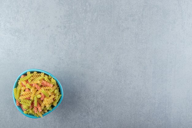 Pâtes fusilli colorées dans un bol bleu.