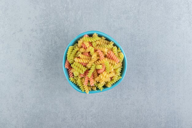 Pâtes fusilli colorées dans un bol bleu.