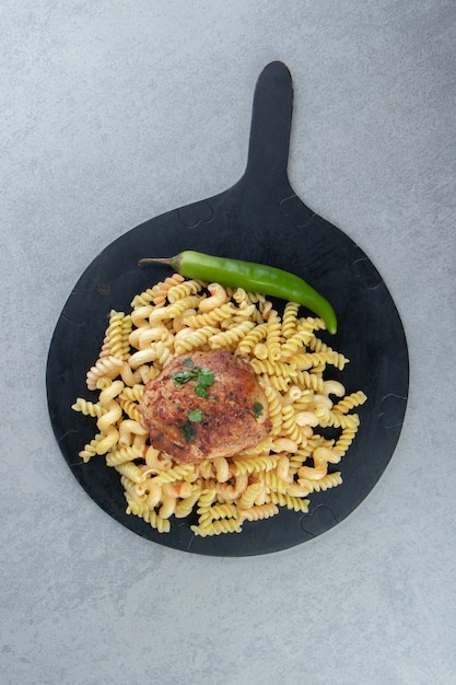 Pâtes fusilli, piment et poulet sur tableau noir.