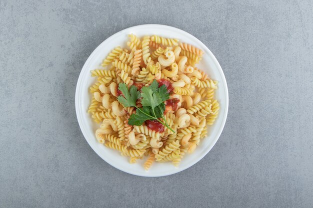 Pâtes fusilli avec sauce sur plaque blanche.