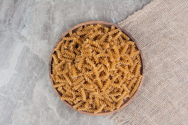 Pâtes maison isolées dans une tasse en bois rustique sur un morceau de toile de jute.