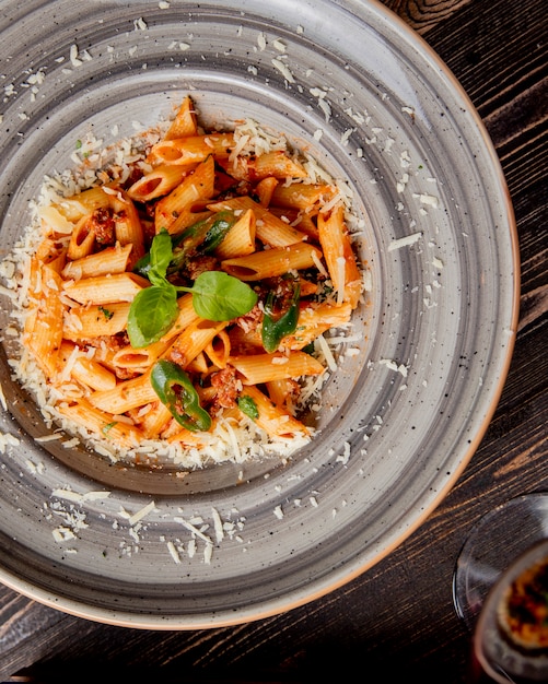 pâtes penne au fromage râpé à la viande et feuille de basilic