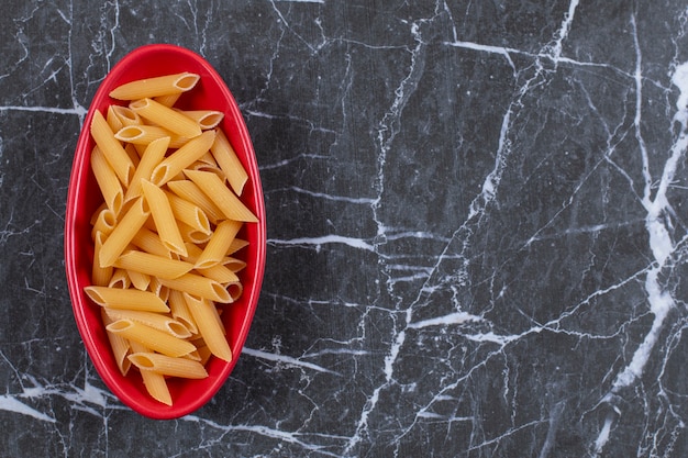 Pâtes Penne Crues Dans Un Bol Rouge Sur Fond Noir.