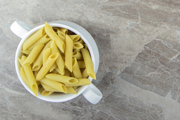 Pâtes penne crues dans une tasse blanche