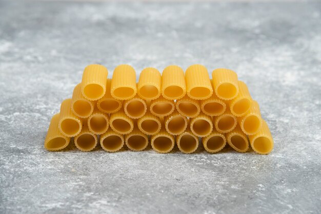 Pâtes penne sur une table en marbre.