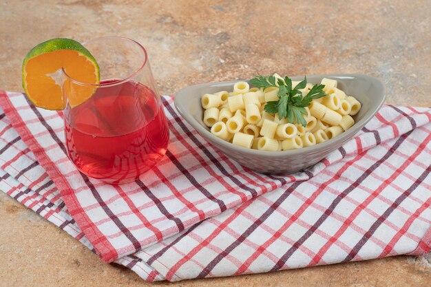 Pâtes penne et verre de cocktail rouge sur nappe