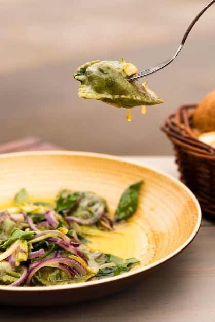 Photo gratuite pâtes de raviolis verts aux oignons et basilic en assiette