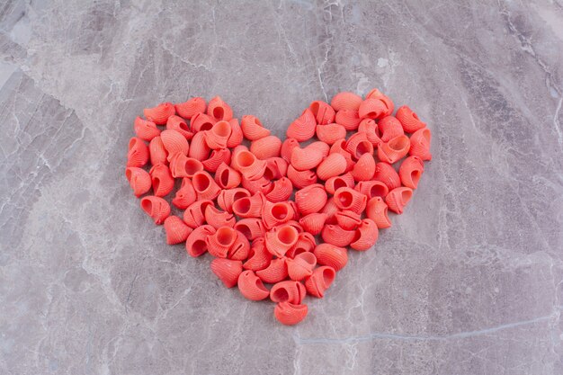 Pâtes rouges en forme de coeur sur la surface en marbre