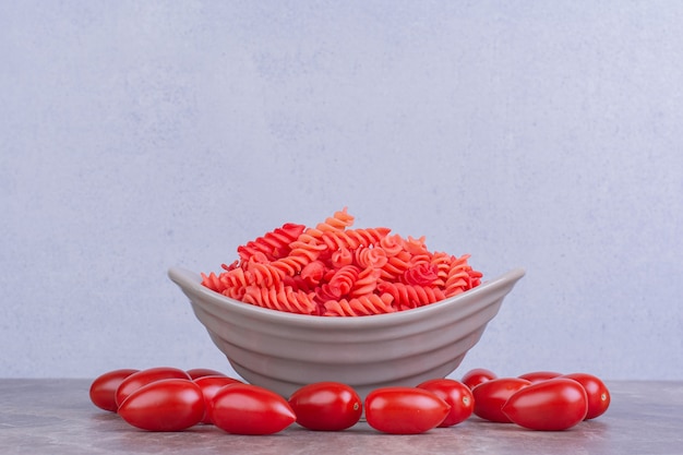 Pâtes rouges non cuites avec des tomates cerises sur la surface en marbre