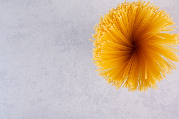 Pâtes spaghetti jaunes non cuites sur la surface de la pierre