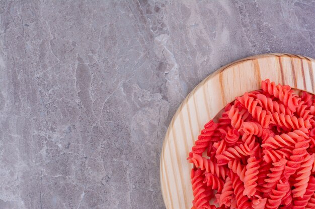 Pâtes en spirale rouge dans un plateau en bois.