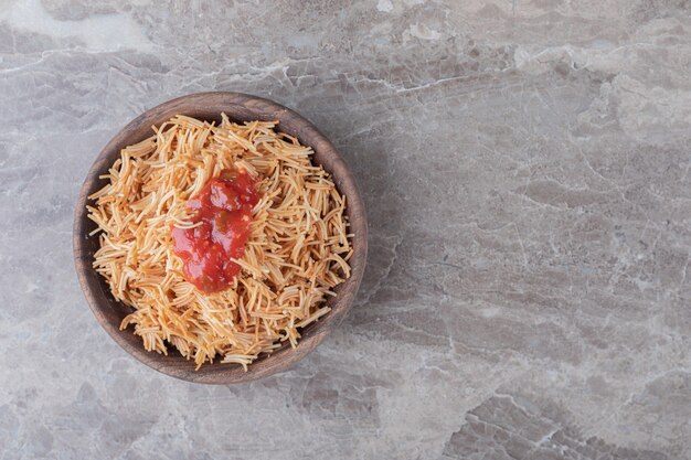 Pâtes vermicelles à la sauce tomate dans le bol , sur la surface en marbre.