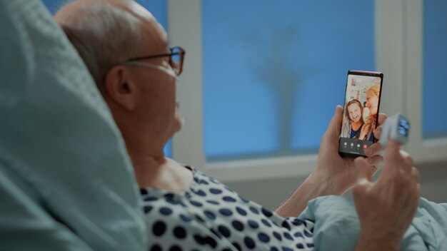 Patient âgé malade parlant par vidéoconférence avec sa famille à l'hôpital