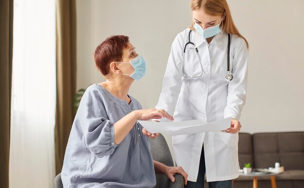 Un patient âgé avec un masque médical et une femme médecin du centre de récupération de covid regardent ensemble les résultats