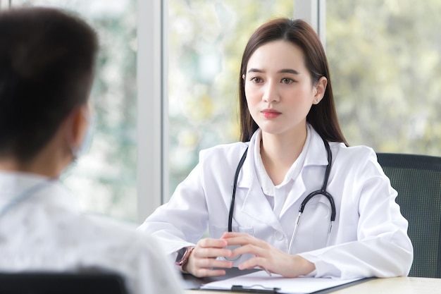 Un patient asiatique âgé consulte une femme médecin professionnelle au sujet de ses symptômes pendant qu'il est médecin
