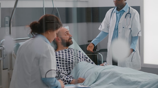 Photo gratuite patient discutant avec des médecins tout en étant allongé dans son lit pendant la convalescence