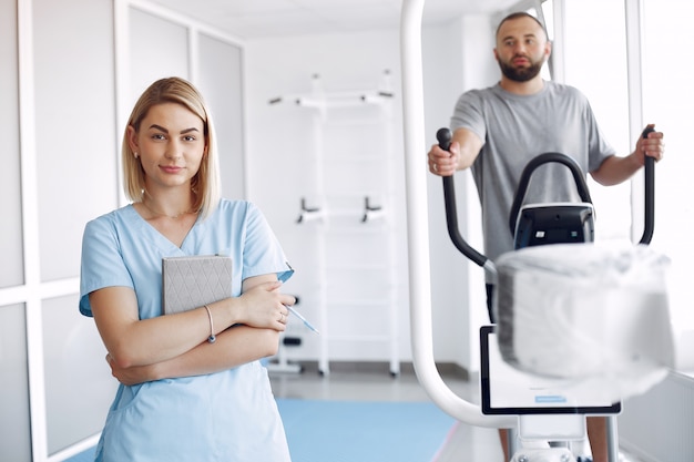 Patient faisant de l'exercice sur spin bike dans une salle de sport avec thérapeute