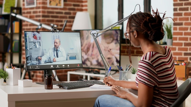 Patient malade parlant à un médecin lors d'une conférence vidéo de télésanté, utilisant un ordinateur avec webcam pour faire une consultation médicale sur une vidéoconférence en ligne. Réunion virtuelle de télémédecine à distance.