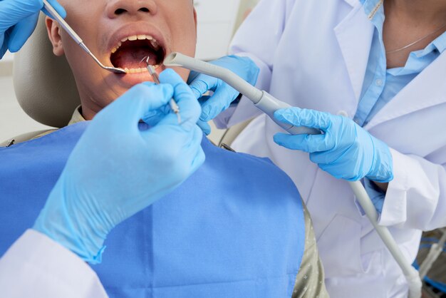 Patient recadré avec la bouche ouverte lors de l'examen dentaire à la dentisterie