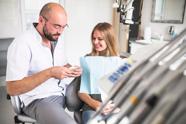 Patiente souriante regardant dentiste travaillant sur la mâchoire dentaire