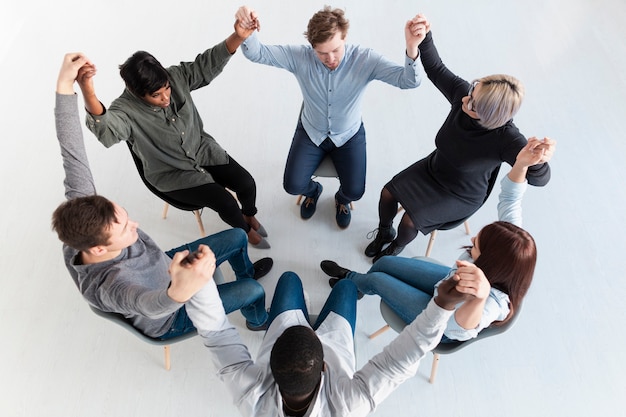 Photo gratuite patients en réadaptation debout en cercle et en levant les mains