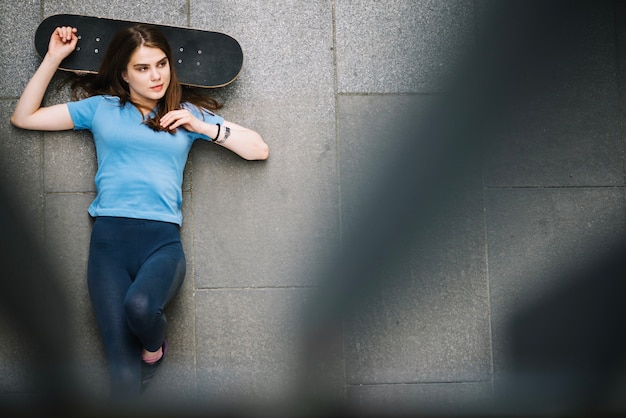 Patineur allongé sur le sol avec planche à roulettes