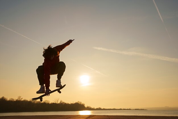 Patineur plein coup posant au coucher du soleil