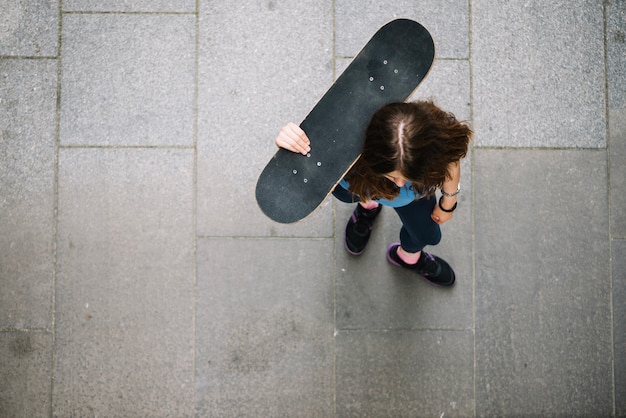 Photo gratuite patineur tenant la planche à roulettes sur l'épaule