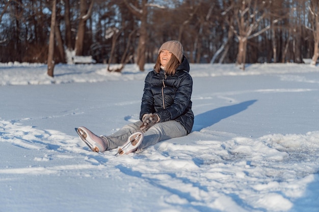 patins à glace, Jeune femme apprend le patinage sur glace, tombe, s'assoit sur la neige, les sports d'hiver, la neige, les plaisirs de l'hiver.
