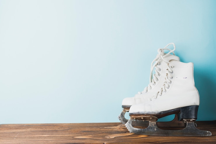 Photo gratuit patins à glace près du mur bleu