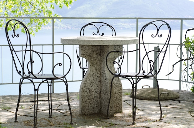 Patio avec table et chaises en pierre avec vue sur un lac