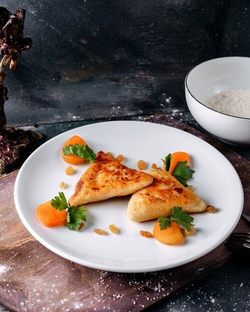 Pâtisserie délicieuse avec des tranches de carotte orange bouillie et des feuilles vertes à l'intérieur de la plaque blanche sur la surface brillante