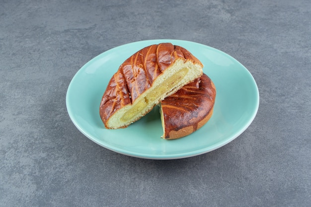 Pâtisserie maison demi-coupée sur plaque bleue.