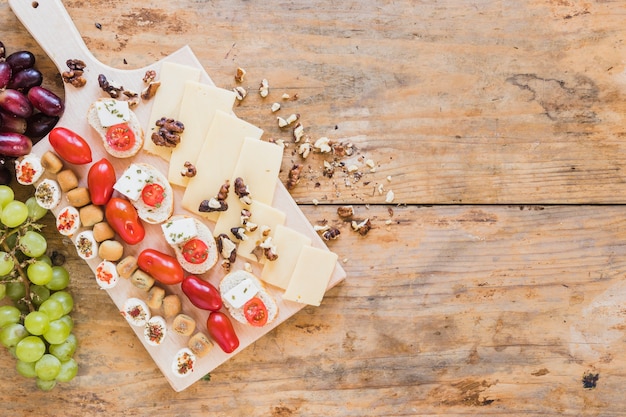 Pâtisserie, sandwichs, tomates, noix et tranches de fromage sur le bureau en bois